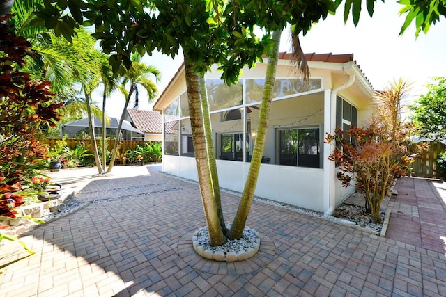 view of front of house featuring a patio, fence, a sunroom, and stucco siding