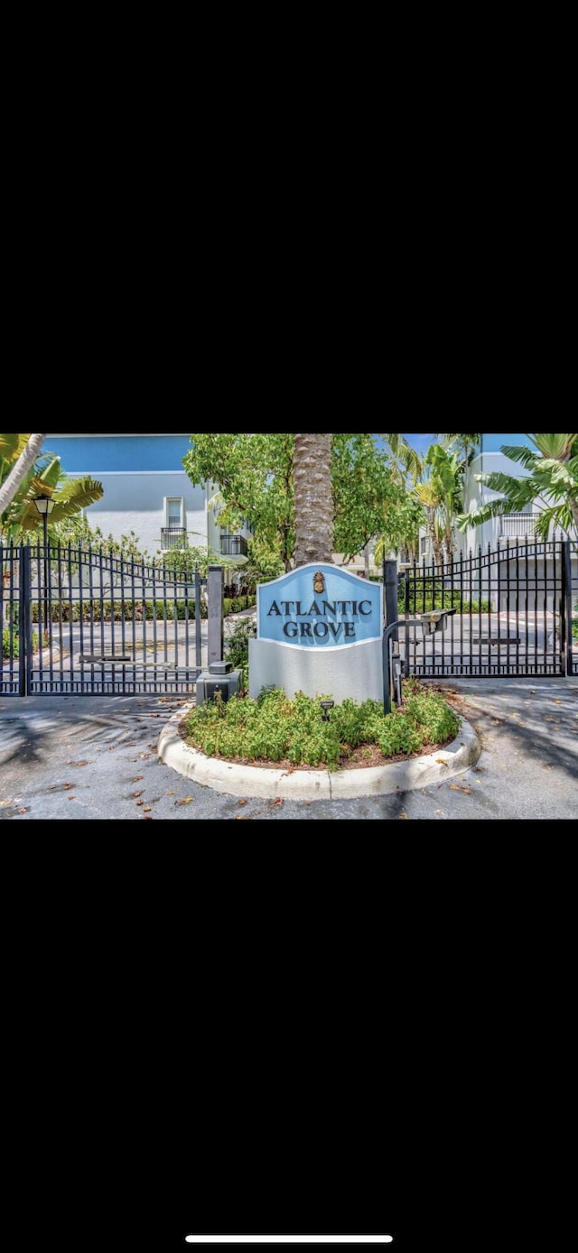 community / neighborhood sign featuring fence and a gate