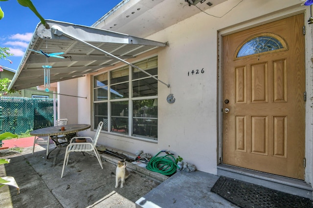 property entrance with a patio area, outdoor dining area, and stucco siding