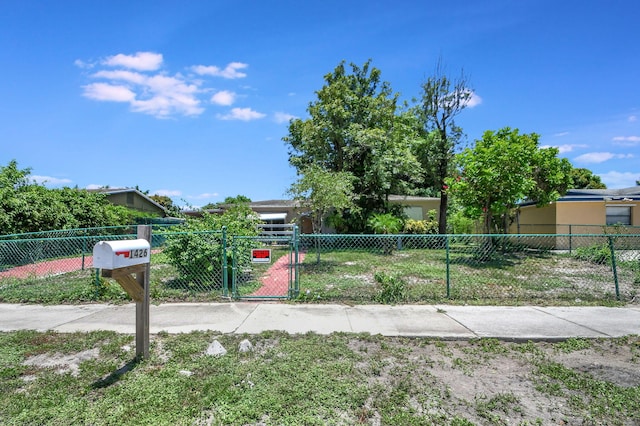 view of property hidden behind natural elements with a fenced front yard and a gate