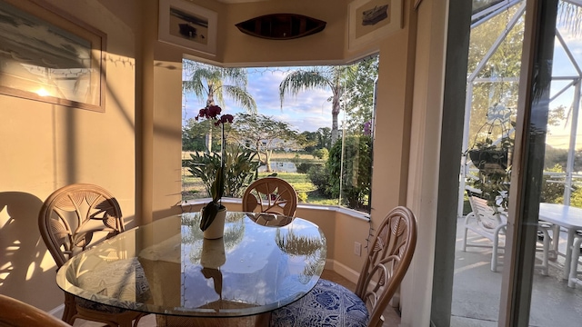 dining room featuring a healthy amount of sunlight, a water view, and baseboards