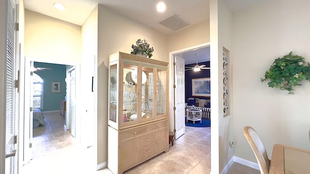hallway with baseboards, visible vents, and a high ceiling