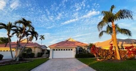 ranch-style house featuring a front lawn, decorative driveway, and an attached garage