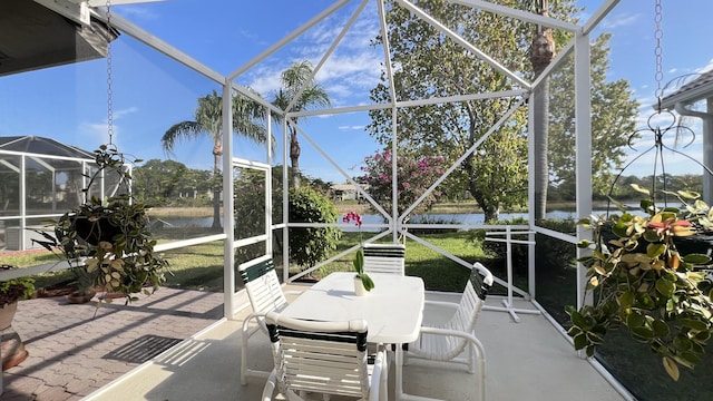 sunroom with outdoor dining area and a water view