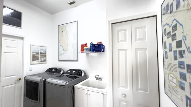 washroom with a sink, washing machine and clothes dryer, cabinet space, and visible vents
