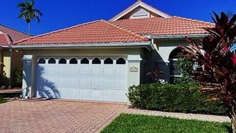 mediterranean / spanish-style house with decorative driveway, an attached garage, a tile roof, and stucco siding
