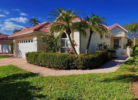 mediterranean / spanish-style house with a garage, stucco siding, and driveway