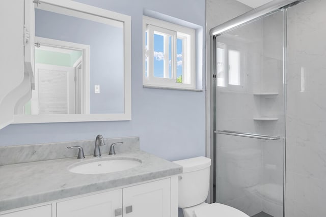 bathroom with vanity, a shower stall, and toilet