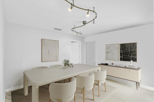 dining room featuring light tile patterned floors, rail lighting, visible vents, and baseboards