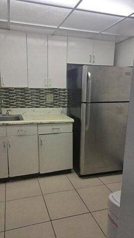 kitchen featuring light tile patterned floors, decorative backsplash, freestanding refrigerator, white cabinets, and a sink