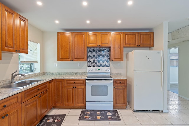 kitchen featuring white appliances, brown cabinets, a sink, and recessed lighting