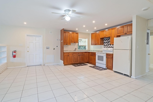 kitchen featuring white appliances, brown cabinets, light countertops, a sink, and recessed lighting