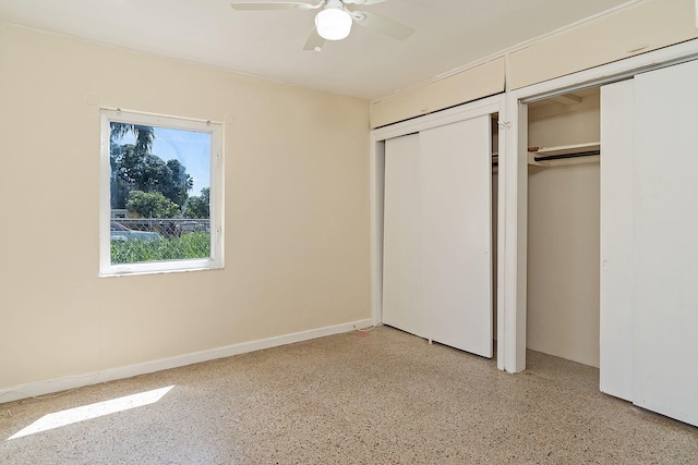 unfurnished bedroom featuring light speckled floor, two closets, a ceiling fan, and baseboards