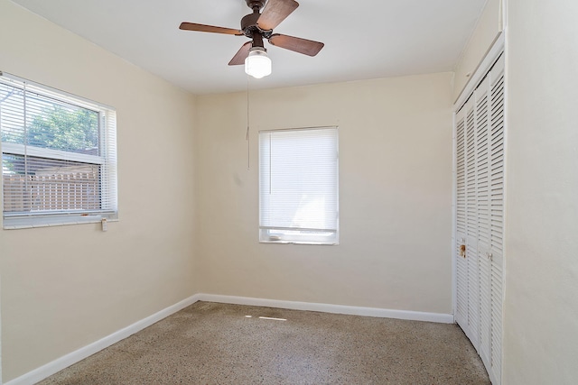 unfurnished bedroom with ceiling fan, baseboards, a closet, and speckled floor