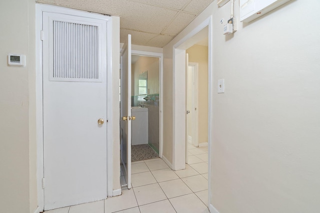 corridor with baseboards, light tile patterned flooring, and a drop ceiling