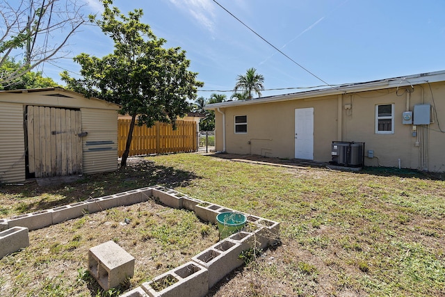 view of yard featuring a vegetable garden, fence, an outdoor structure, and a shed