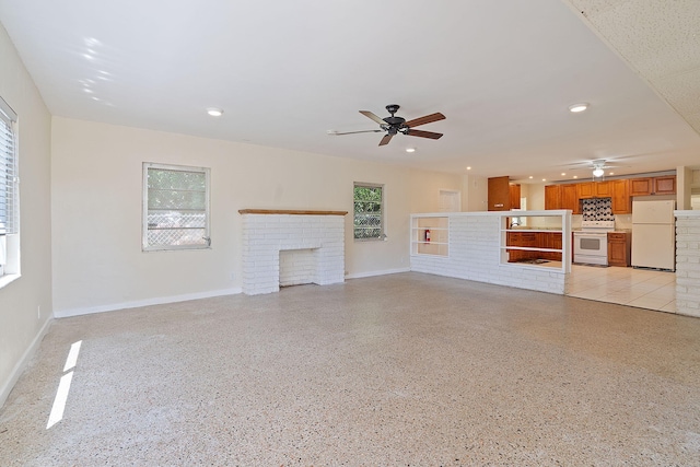 unfurnished living room featuring light speckled floor, ceiling fan, recessed lighting, a fireplace, and baseboards