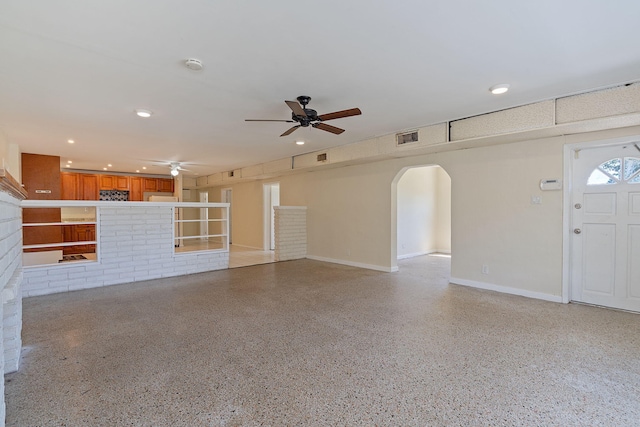 unfurnished living room with light speckled floor, ceiling fan, arched walkways, and visible vents