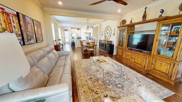 living room featuring ceiling fan with notable chandelier, crown molding, recessed lighting, and wood finished floors