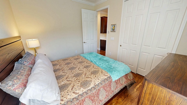 bedroom with a closet, crown molding, and wood finished floors