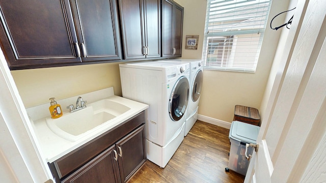 laundry room featuring cabinet space, light wood-style flooring, a sink, independent washer and dryer, and baseboards