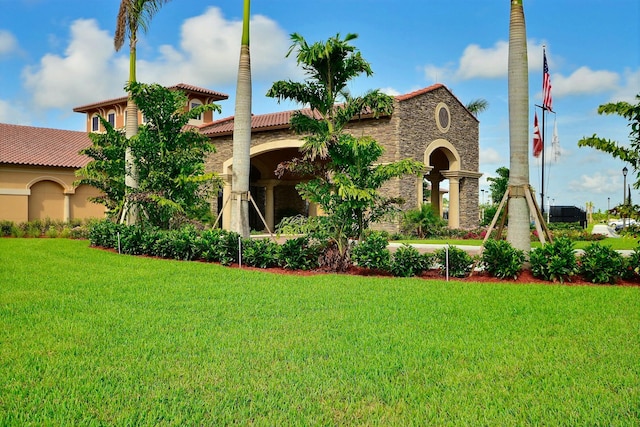 view of front of house with stucco siding, a tile roof, stone siding, and a front yard