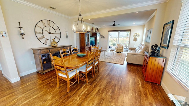 dining area with ceiling fan with notable chandelier, wood finished floors, visible vents, baseboards, and ornamental molding