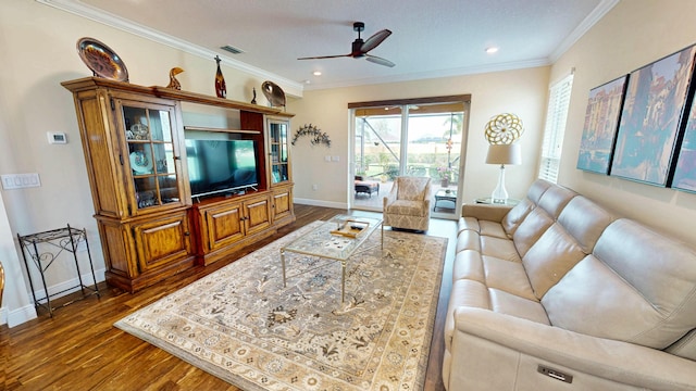 living area featuring dark wood-style flooring, crown molding, visible vents, a ceiling fan, and baseboards