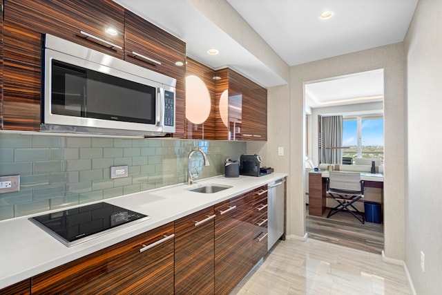 kitchen with stainless steel appliances, light countertops, backsplash, a sink, and modern cabinets