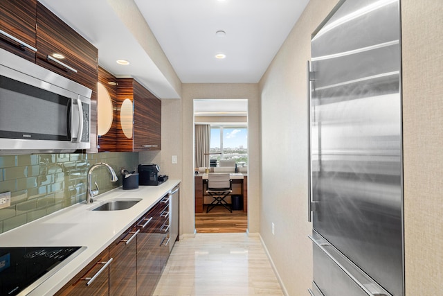 kitchen with appliances with stainless steel finishes, tasteful backsplash, a sink, and modern cabinets