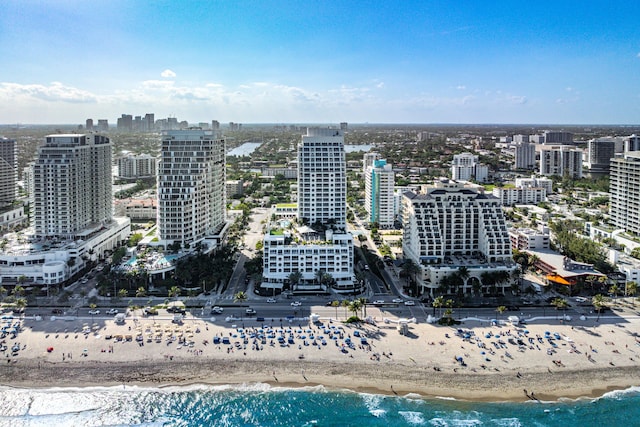 drone / aerial view featuring a water view, a city view, and a view of the beach