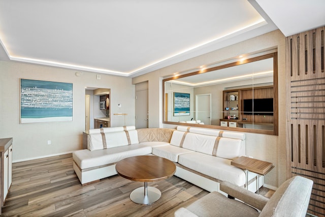 living room with a raised ceiling, baseboards, and wood finished floors