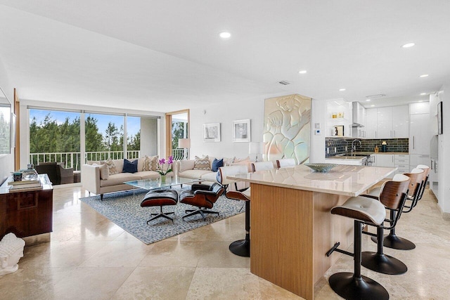 kitchen with recessed lighting, white cabinetry, decorative backsplash, expansive windows, and a kitchen bar