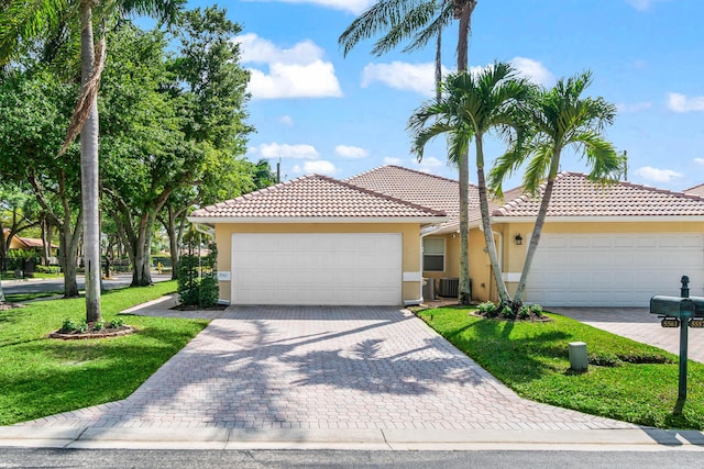 view of front of home with stucco siding, an attached garage, cooling unit, a tiled roof, and a front lawn