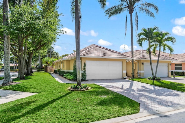 ranch-style house with an attached garage, a tile roof, a front yard, and stucco siding