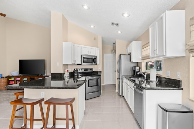 kitchen featuring light tile patterned flooring, a sink, visible vents, appliances with stainless steel finishes, and a kitchen bar