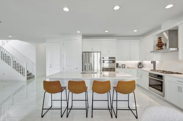 1396 Bushel Creek Xing, Loxahatchee, FL 33470 - kitchen featuring stainless steel appliances, wall chimney exhaust hood, a breakfast bar area, a kitchen island with sink, and recessed lighting