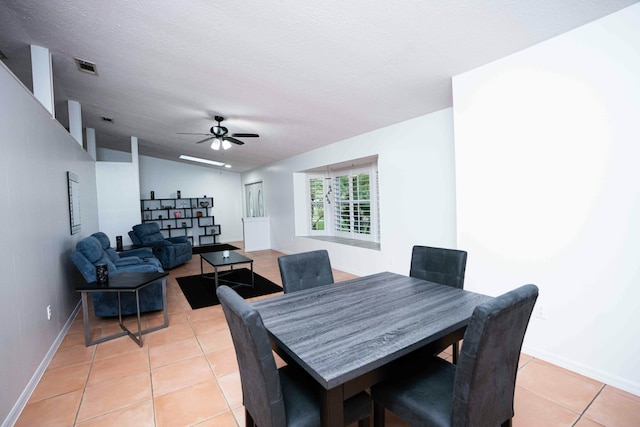 dining room featuring light tile patterned floors, ceiling fan, baseboards, a textured ceiling, and lofted ceiling