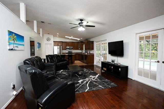 living area featuring vaulted ceiling, a ceiling fan, wood finished floors, healthy amount of natural light, and baseboards