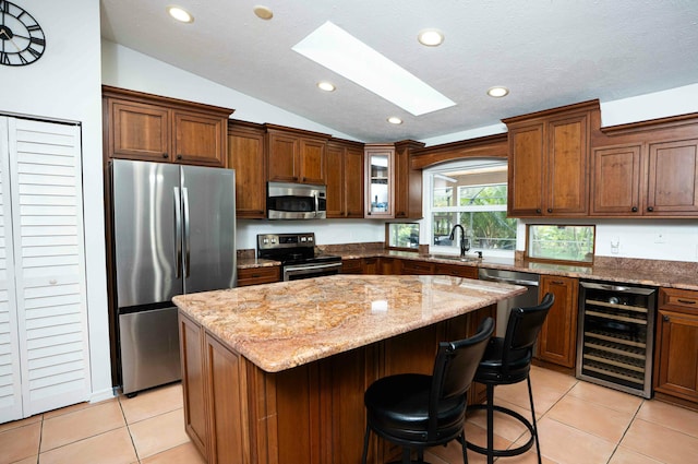kitchen featuring stainless steel appliances, beverage cooler, vaulted ceiling, a skylight, and light tile patterned floors