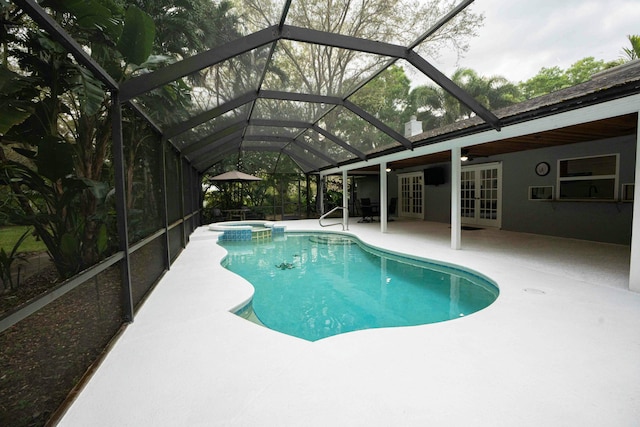 view of pool featuring glass enclosure, french doors, a patio area, and a pool with connected hot tub