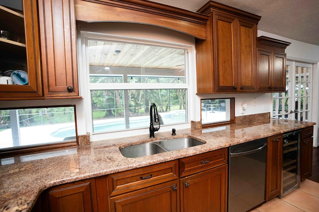 kitchen with a sink, dishwasher, beverage cooler, and light stone countertops