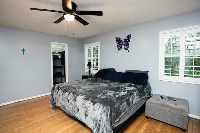 bedroom featuring light wood-style floors, baseboards, a ceiling fan, and a textured ceiling