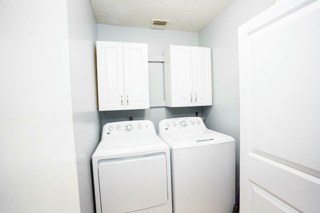 laundry room featuring cabinet space, separate washer and dryer, and a textured ceiling