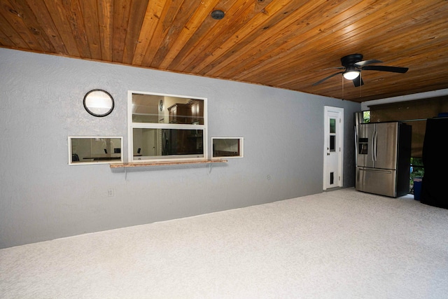 unfurnished living room featuring carpet flooring, wooden ceiling, a ceiling fan, and a textured wall
