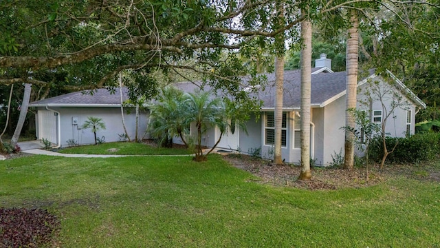 back of property with stucco siding, a yard, a shingled roof, and an attached garage