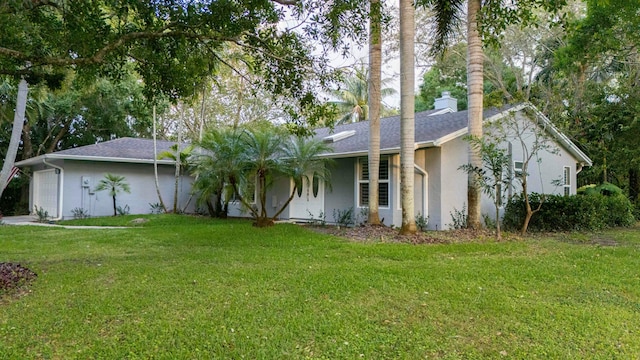 view of front facade with stucco siding, a chimney, a front lawn, and roof with shingles
