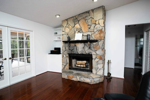 unfurnished living room with baseboards, a stone fireplace, and wood finished floors