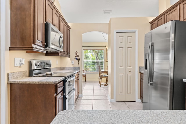 kitchen featuring arched walkways, light tile patterned floors, visible vents, light countertops, and appliances with stainless steel finishes