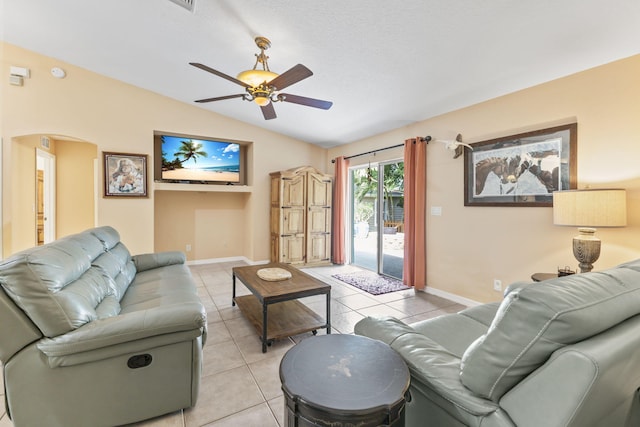 living room featuring ceiling fan, arched walkways, vaulted ceiling, and light tile patterned flooring